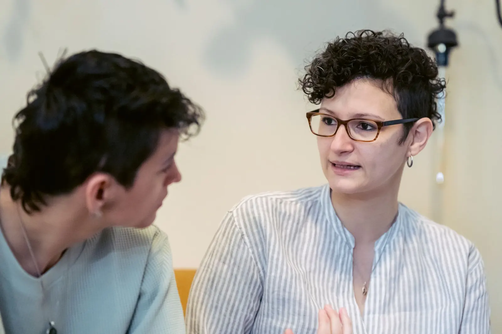 Zwei Menschen sitzen sich im warmen Tageslicht gegenüber und sprechen konzentriert miteinander